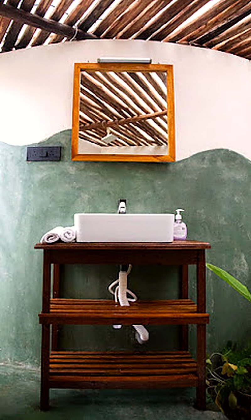A teak vanity and basin against green plaster