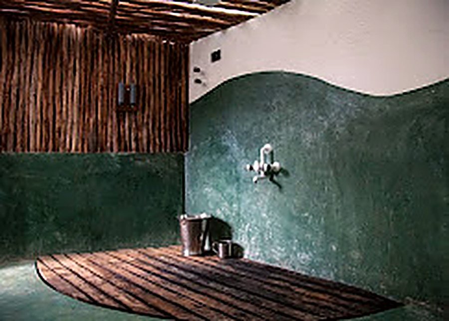 A washroom with green lime plaster walls and a teak deck